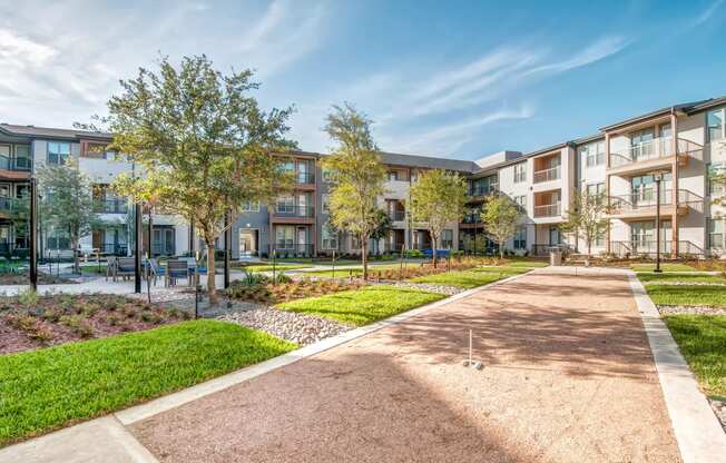 a pathway leading to an apartment building with grass and trees