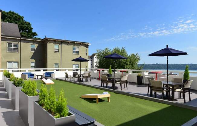 A patio with tables and chairs overlooking a body of water.