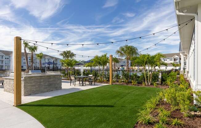 the yard has a patio with a table and chairs and green grass