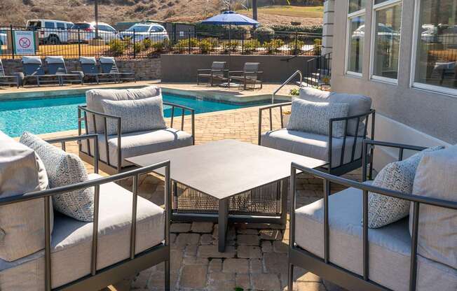 a patio with chairs and a table next to a pool