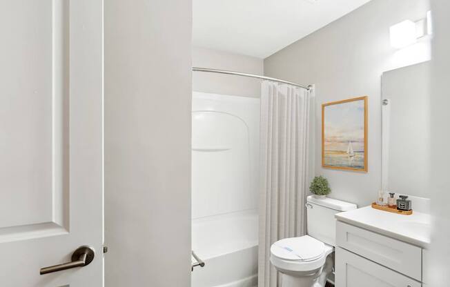 A white bathroom with a toilet, sink, and shower.