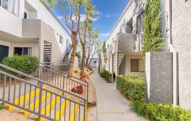 a pathway between two apartment buildings with a blue sky in the background