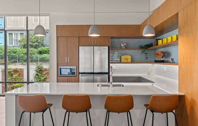 A modern kitchen with a bar area and orange chairs.