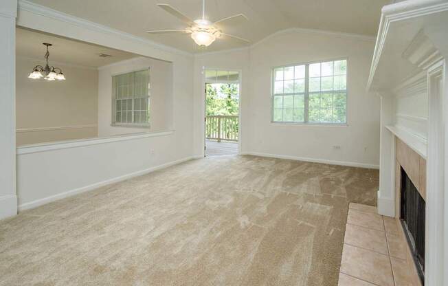 A spacious living room with a fireplace and a ceiling fan.