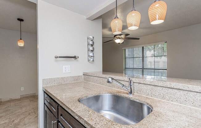 A modern bathroom with a granite countertop and a stainless steel sink.