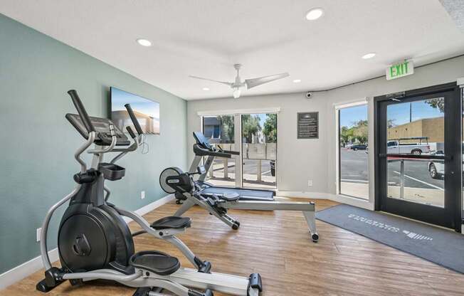 A gym with a row of exercise bikes and a treadmill.