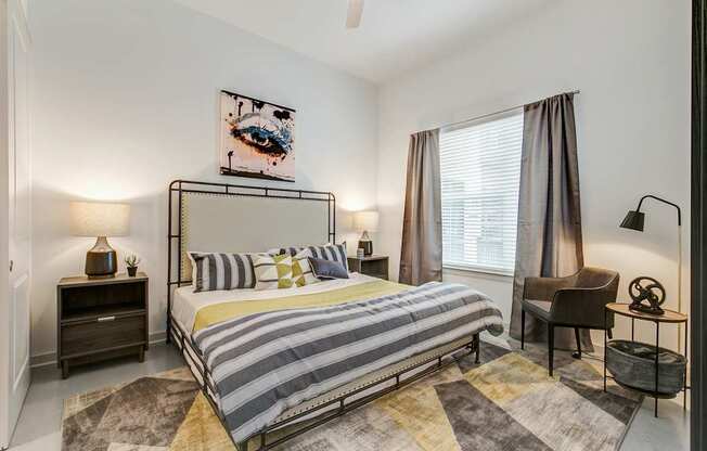 A bedroom with a bed, nightstands, and a chair.