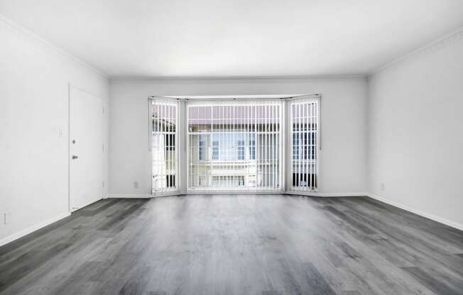 an empty living room with a large window and wooden floors