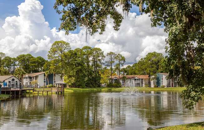 A serene lake surrounded by houses and trees under a cloudy sky.