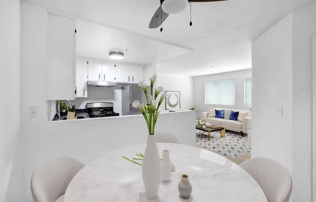 a white kitchen and dining room with a white table