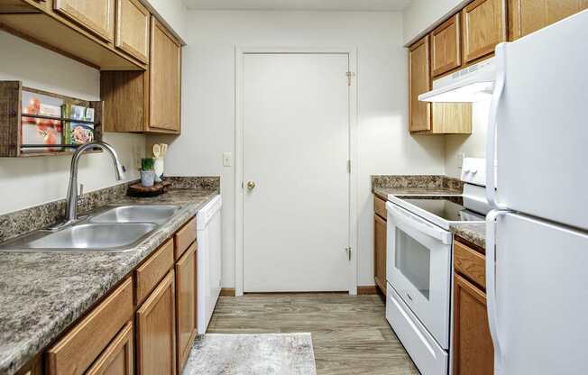A kitchen with a white refrigerator, sink, and cabinets.