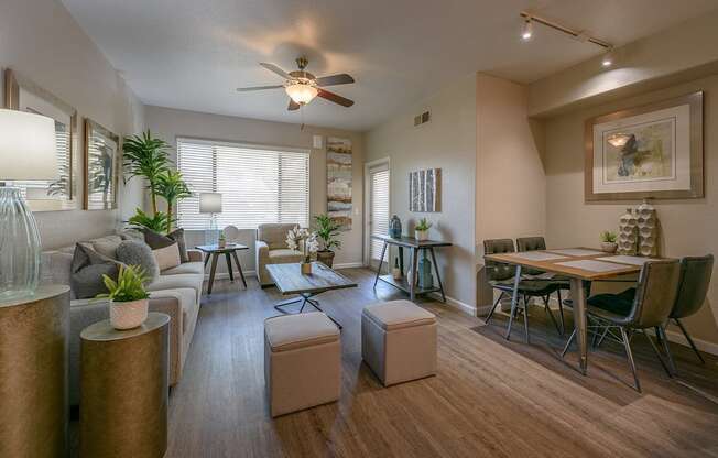 A living room with a grey couch, a wooden table, and a ceiling fan.