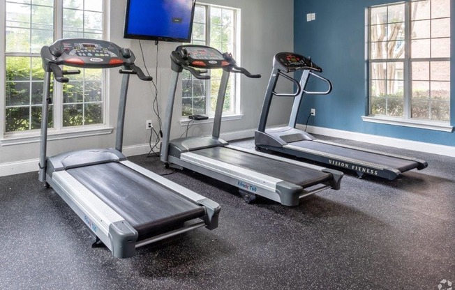 three treadmills and a tv in an exercise room