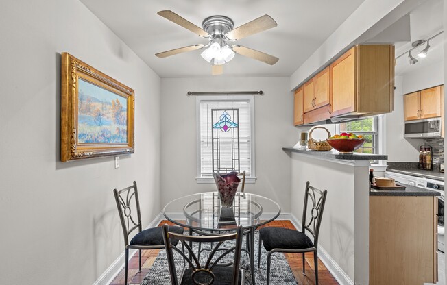 a dining room with a glass table and chairs and a ceiling fan