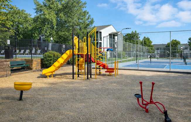 A playground with a yellow slide and red monkey bars.