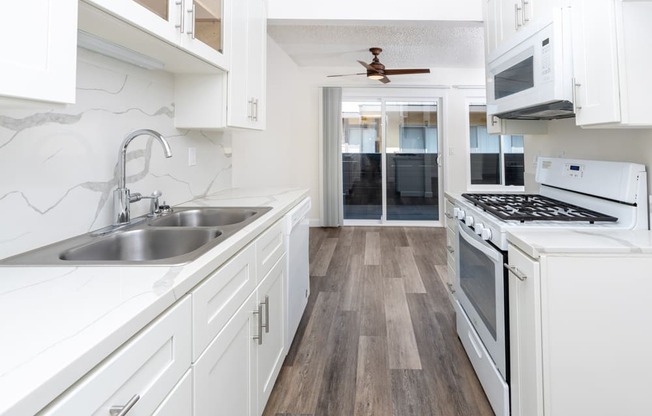 a kitchen with white cabinets and a stove and a sink