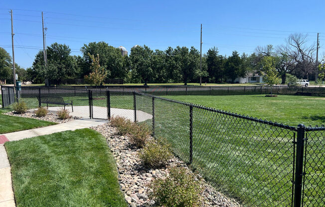 a dog park with a bench and fence at Copper Creek Apartments in Maize, KS