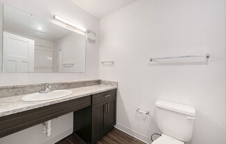 a bathroom with a toilet and a sink and a mirror at Trade Winds Apartment Homes, Elkhorn, Nebraska