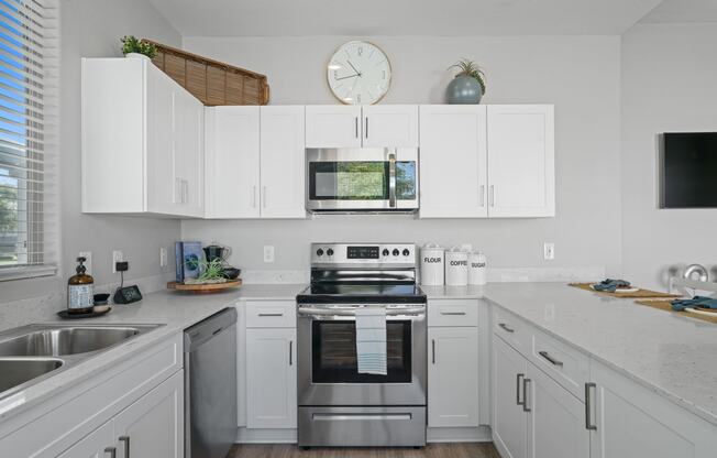 a kitchen with white cabinets and stainless steel appliances and a clock
