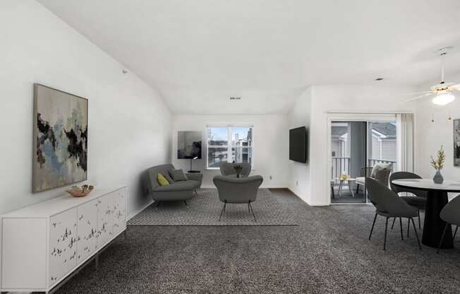 the living room and dining area of an apartment with white walls and carpet