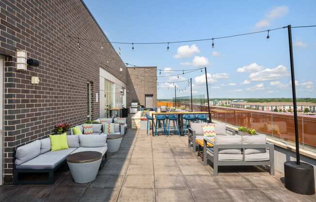 a rooftop terrace with couches and tables and a brick wall