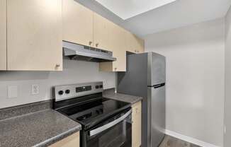 A kitchen with a black stove top oven and a stainless steel refrigerator.