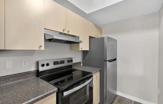 A kitchen with a black stove top oven and a stainless steel refrigerator.