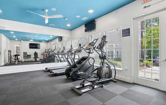 A gym with a variety of equipment including treadmills, weights, and a television.