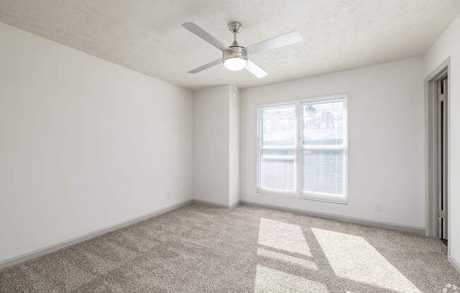 A room with a ceiling fan and carpeted floor.