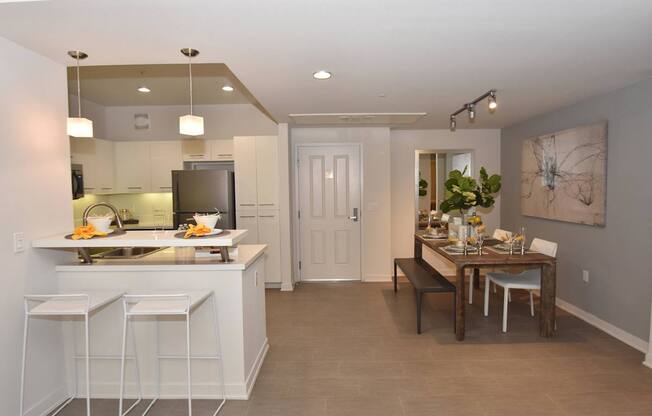 A kitchen with white cabinets and a bar area.