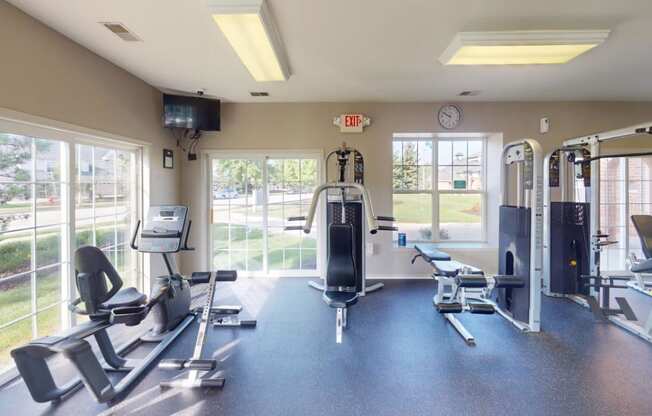 a gym with weights and cardio equipment and windows