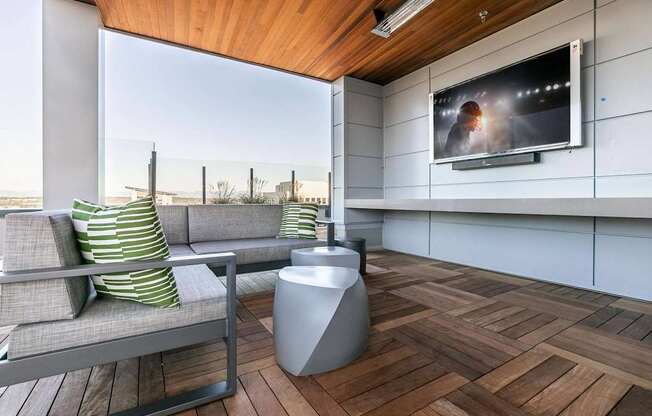 A modern living room with a grey sofa and a television on the wall.