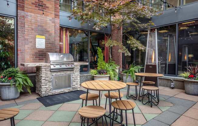 A patio with a table and chairs and a grill.
