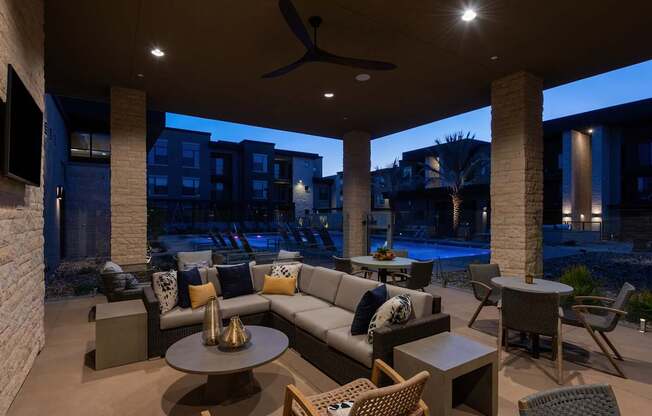 A patio with a couch, chairs, and a table with a fan.