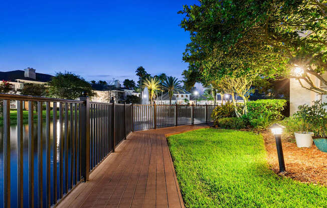 A walkway with lights and a fence next to a body of water.
