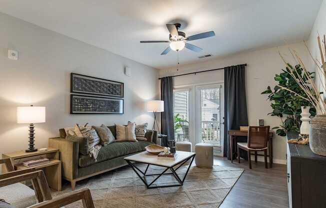 A living room with a green couch, a coffee table, and a ceiling fan.