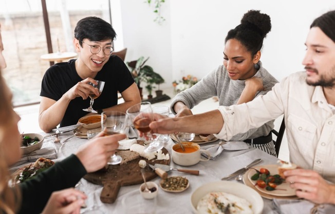 five friends eating at a table drinking wine