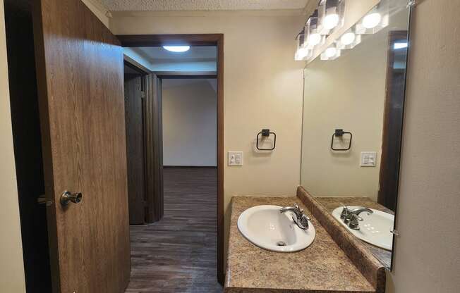 a bathroom with a sink and a mirror and a door