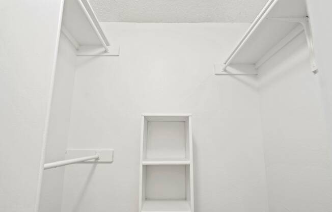 a white wall with two white shelves and a white ladder on the side of the wall
