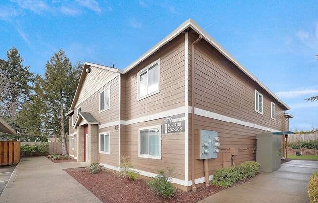 A brown house with a garage door and a mailbox on the front.