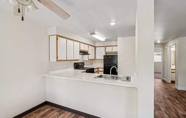 A kitchen with white cabinets and a wooden floor.