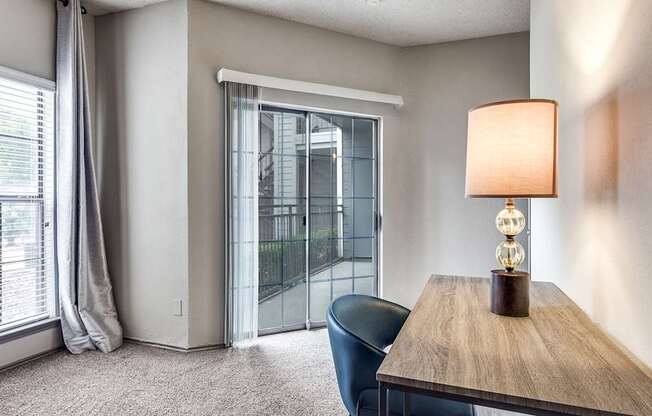 A room with a table, chair, and a lamp.
