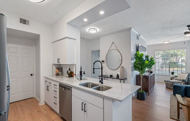 an open kitchen and living room with white cabinets and a sink