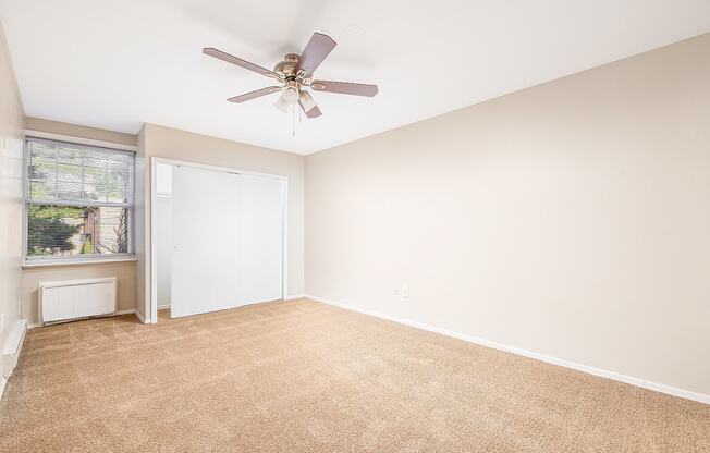A room with a ceiling fan and carpeted floor.