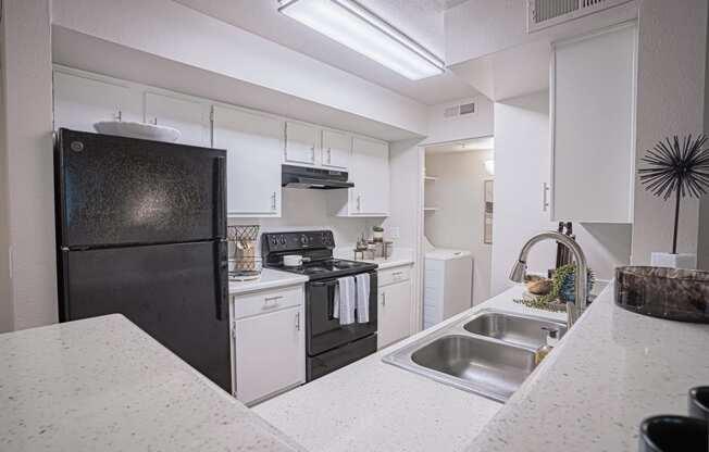 a kitchen with white cabinets and a black refrigerator