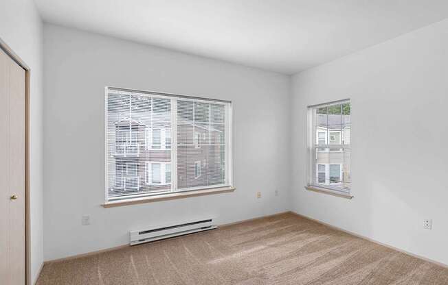a living room with two windows and a carpeted floor