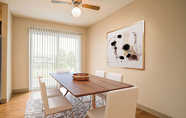 a dining room with a ceiling fan and a large painting on the wall