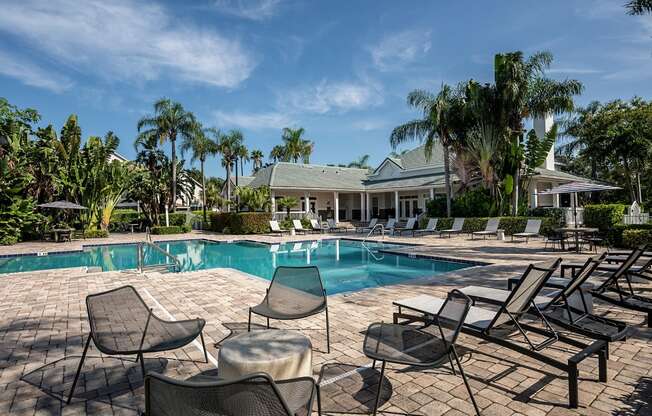 a swimming pool with chairs and a house in the background