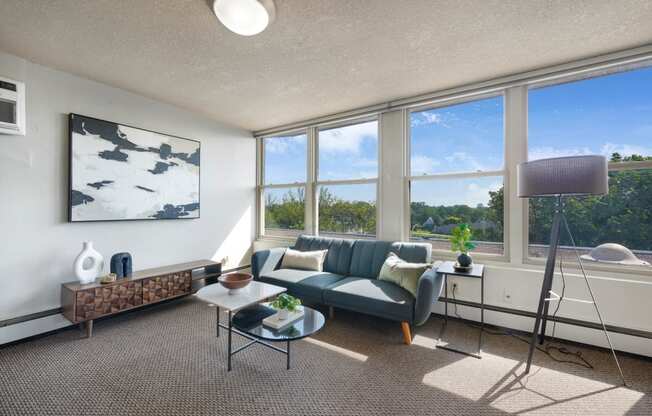 the living room of an apartment with a blue couch and a large window