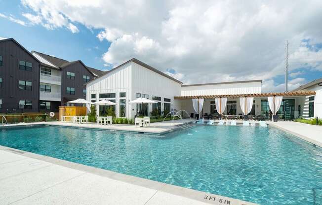 a large swimming pool with umbrellas and chairs in front of a building